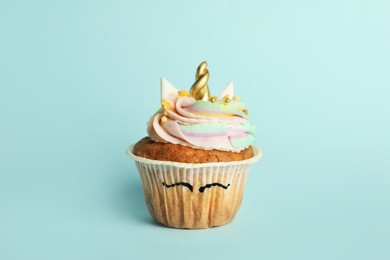 Photo of Cute sweet unicorn cupcake on light turquoise background