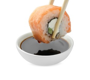 Dipping tasty sushi into soy sauce isolated on white