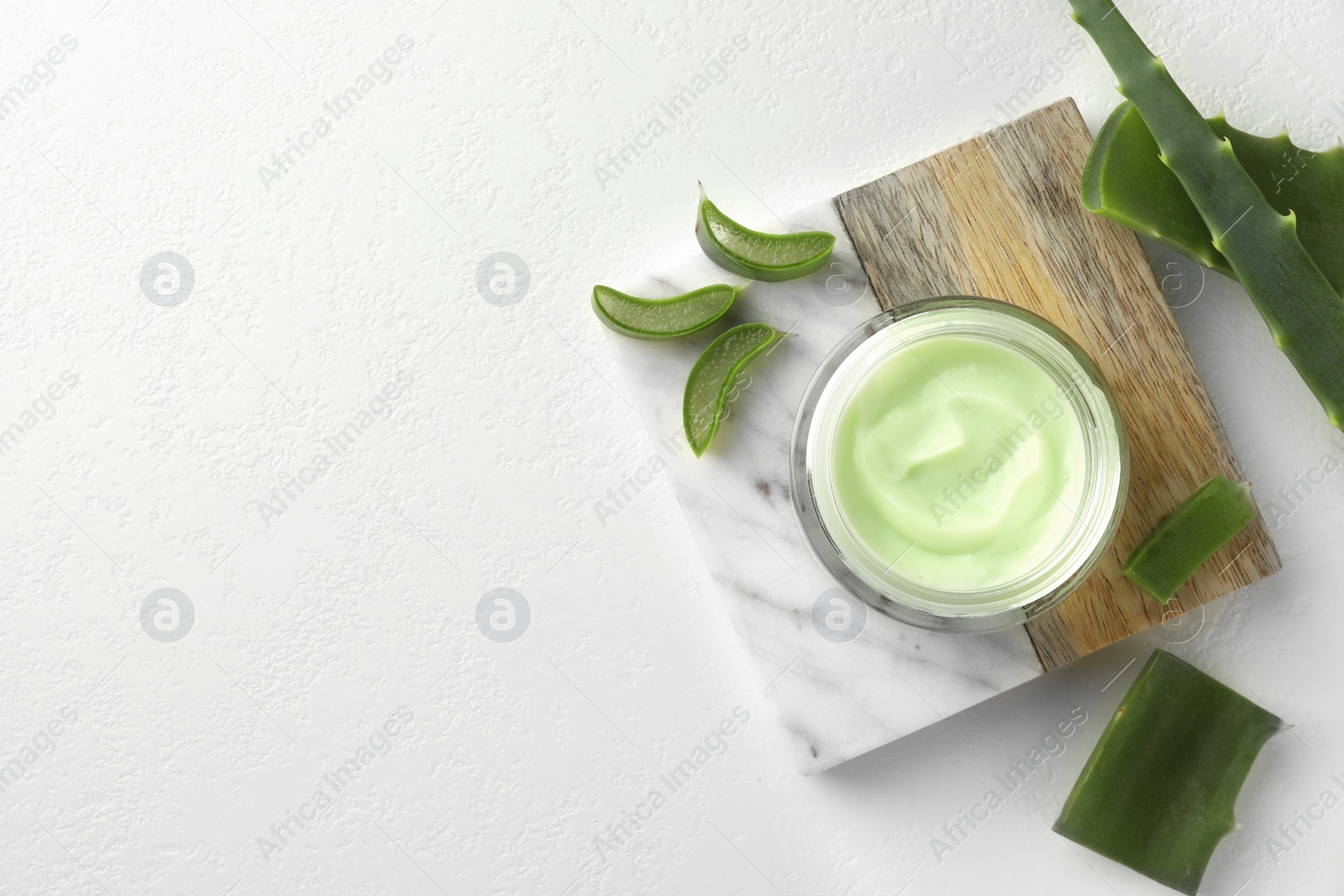 Photo of Jar with cream and cut aloe leaves on white table, flat lay. Space for text