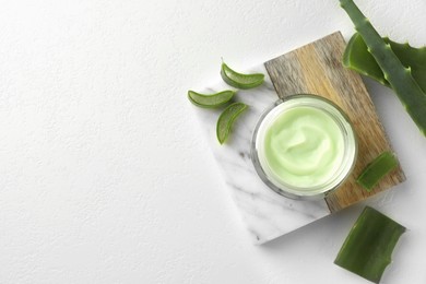 Jar with cream and cut aloe leaves on white table, flat lay. Space for text