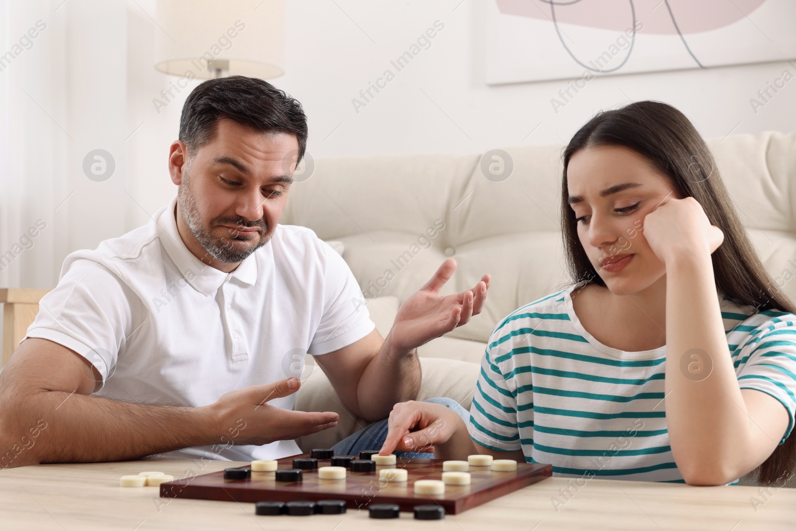 Photo of Couple playing checkers at table in room