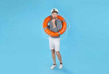 Photo of Thoughtful sailor with orange ring buoy on light blue background