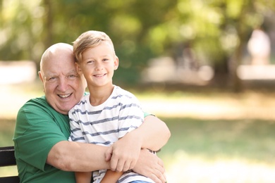 Photo of Elderly man with grandson on bench in park
