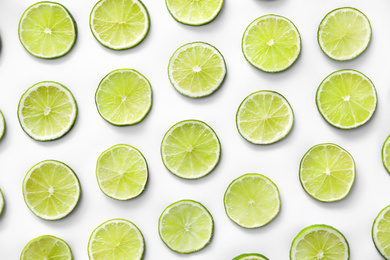 Photo of Slices of fresh juicy limes on white background, flat lay