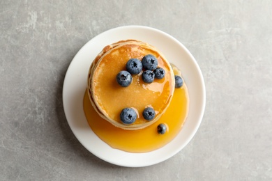 Photo of Plate with pancakes and berries on grey background, top view