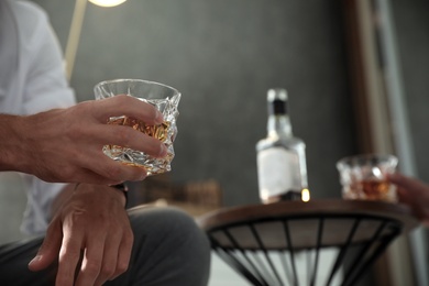 Man with glass of whiskey indoors, closeup view. Space for text