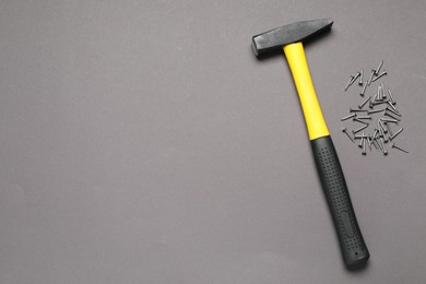 Photo of Hammer and metal nails on grey background, flat lay. Space for text