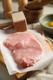 Photo of Raw pork chops, meat mallet and ingredients for cooking schnitzel on grey table