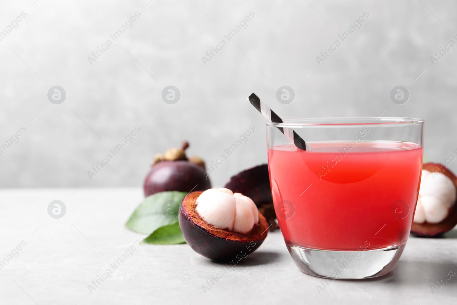 Photo of Delicious fresh mangosteen juice in glass on light grey table, space for text