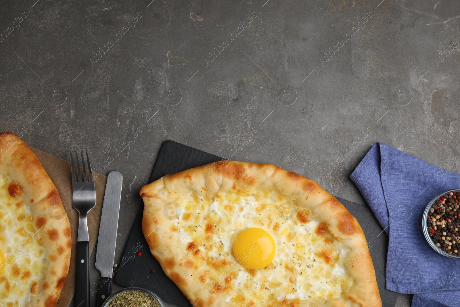 Photo of Fresh homemade khachapuri with cheese and egg served on grey table, flat lay. Space for text