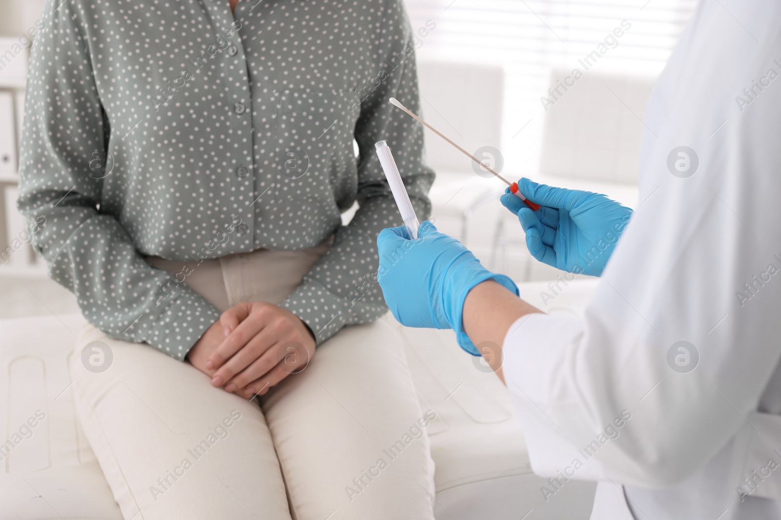 Photo of Doctor taking sample for STD testing from woman in clinic, closeup