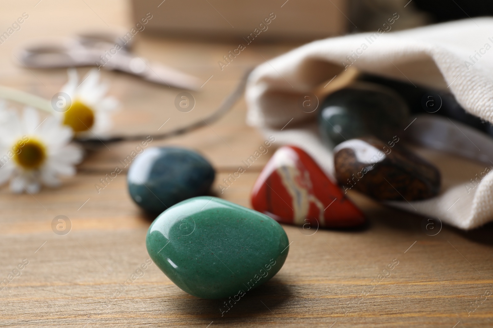 Photo of Different healing gemstones on wooden table, closeup