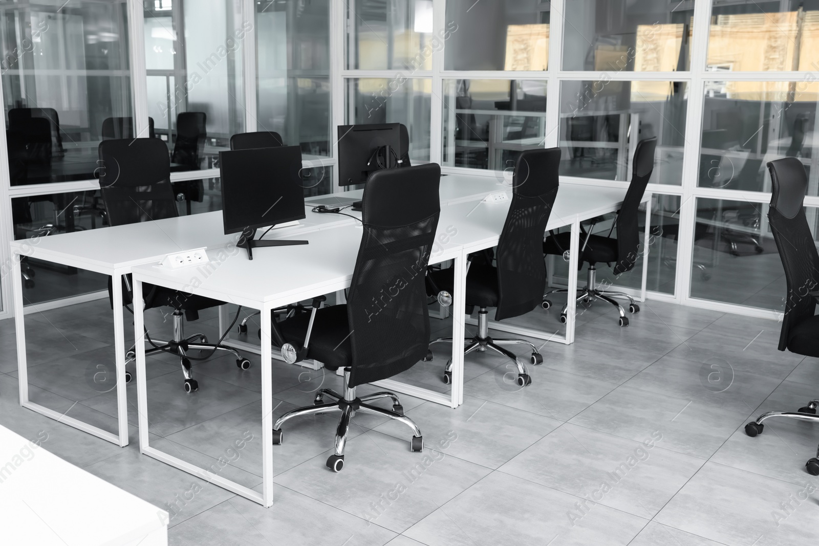 Photo of Stylish interior of open plan office. Workspace with computers, tables and chairs