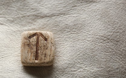 Photo of Wooden rune Teiwaz on leather, closeup. Space for text