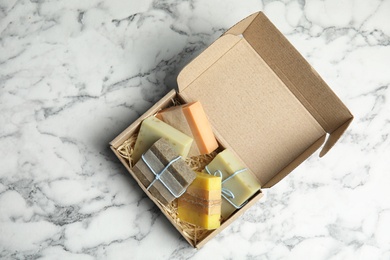 Cardboard box with different handmade soap bars on table, top view