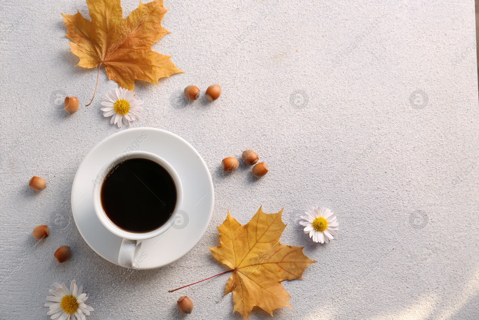 Photo of Flat lay composition with cup of hot drink and autumn leaves on light grey textured table. Space for text