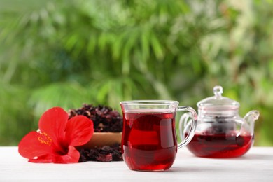 Delicious hibiscus tea and flowers on white wooden table outdoors, space for text