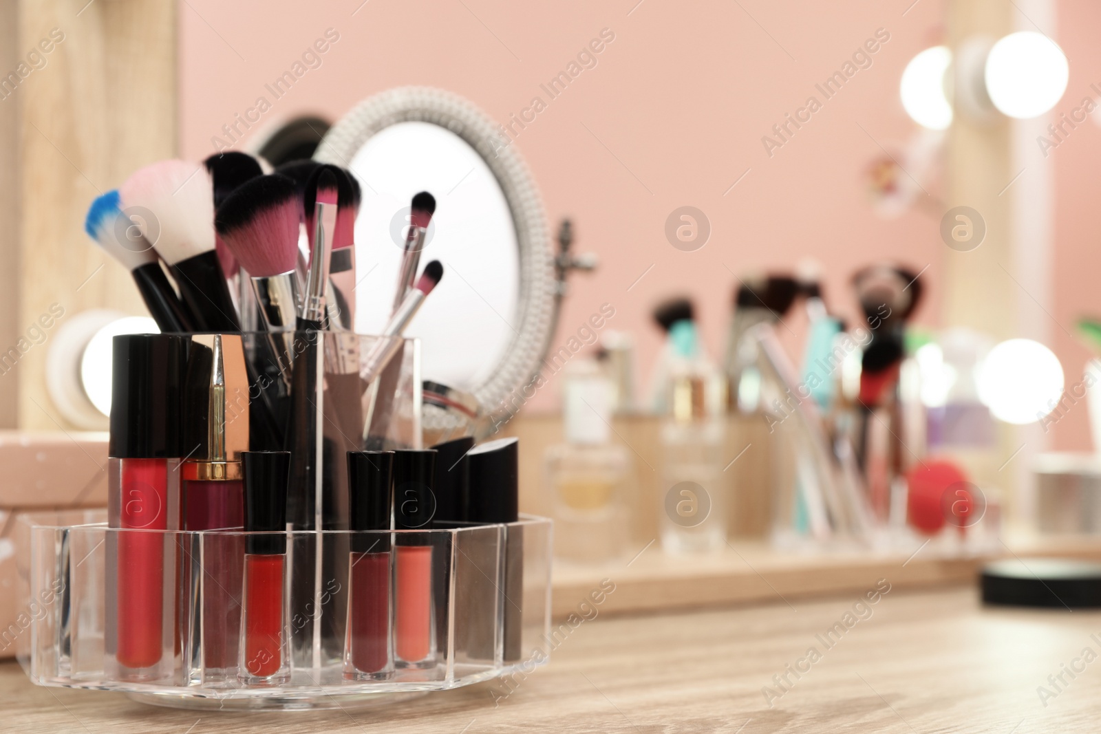 Photo of Organizer with cosmetic products for makeup on table near mirror. Space for text