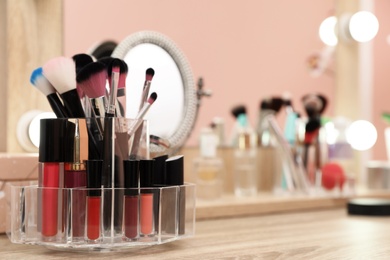 Photo of Organizer with cosmetic products for makeup on table near mirror. Space for text