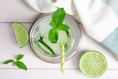 Glass of refreshing cucumber water with mint on white wooden table, flat lay