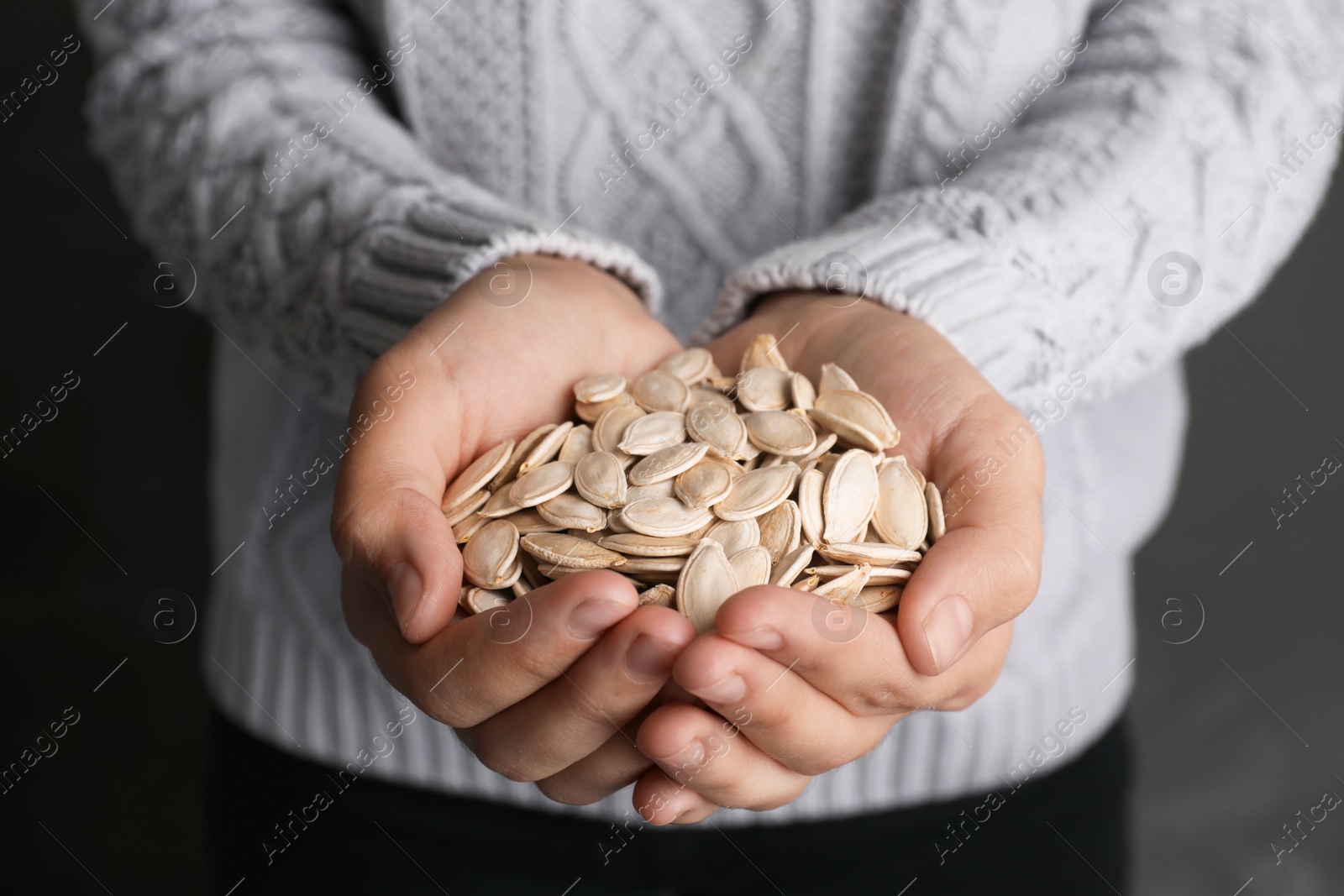 Photo of Woman holding raw pumpkin seeds, closeup view