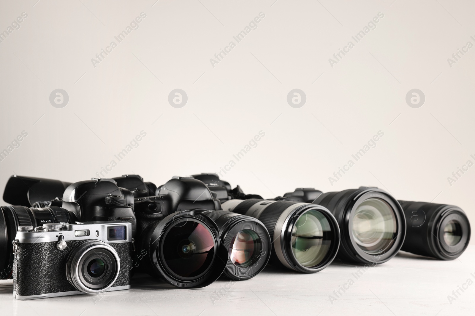 Photo of Modern cameras on white wooden table, space for text