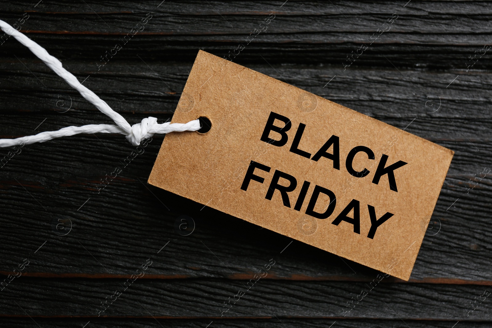Photo of Blank tag on dark wooden background, top view. Black Friday concept