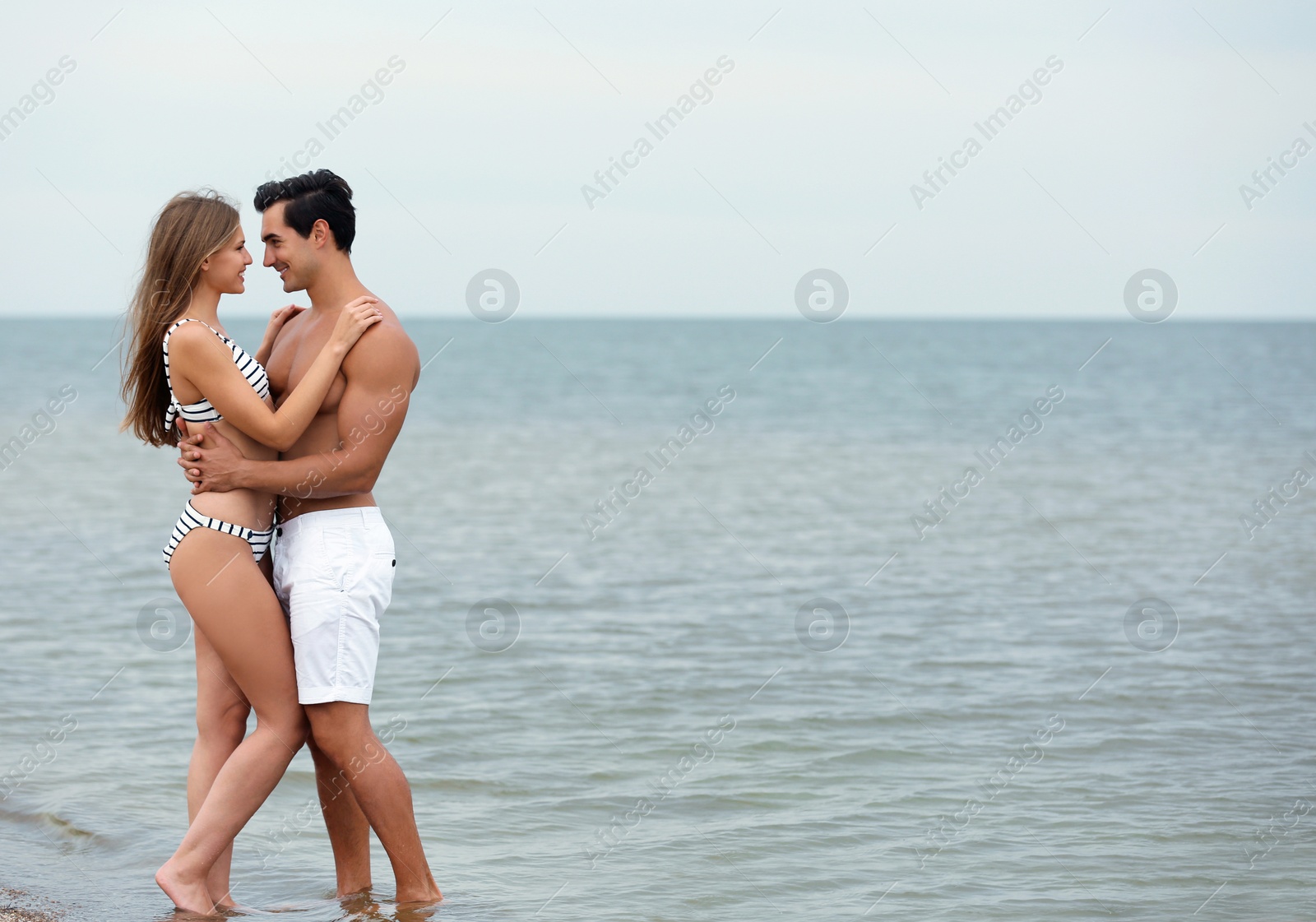 Photo of Happy young couple spending time together on sea beach. Space for text