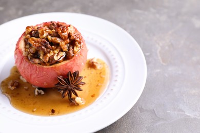 Photo of Tasty baked apple with nuts, honey and anise on gray table, closeup