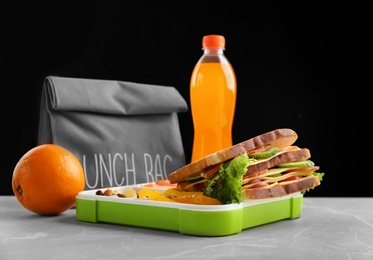 Lunch box with appetizing food and bag on table