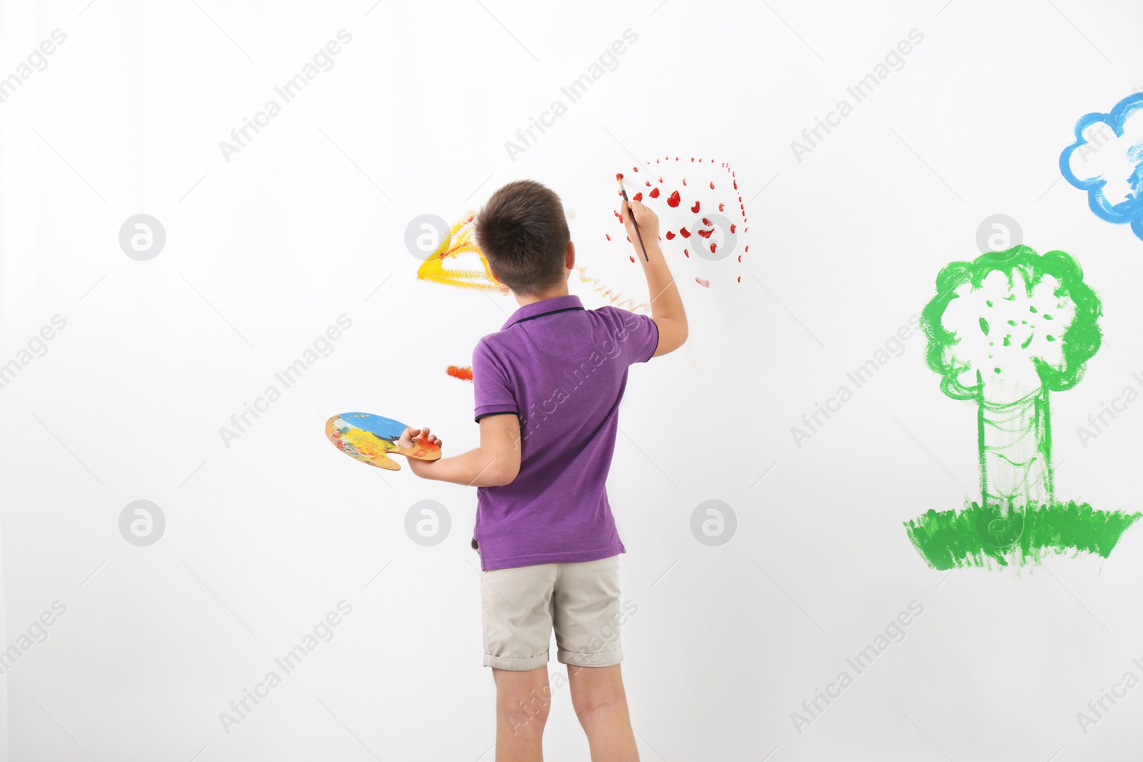 Photo of Little child painting on white wall indoors