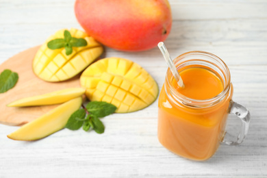 Photo of Fresh delicious mango drink on white wooden table