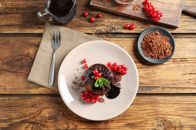 Photo of Delicious warm chocolate lava cake with mint and berries on wooden table, flat lay