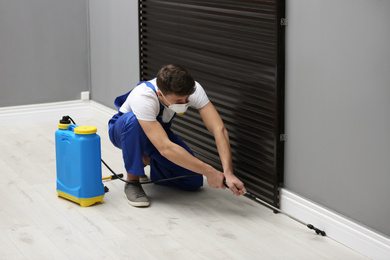 Photo of Pest control worker spraying pesticide in room