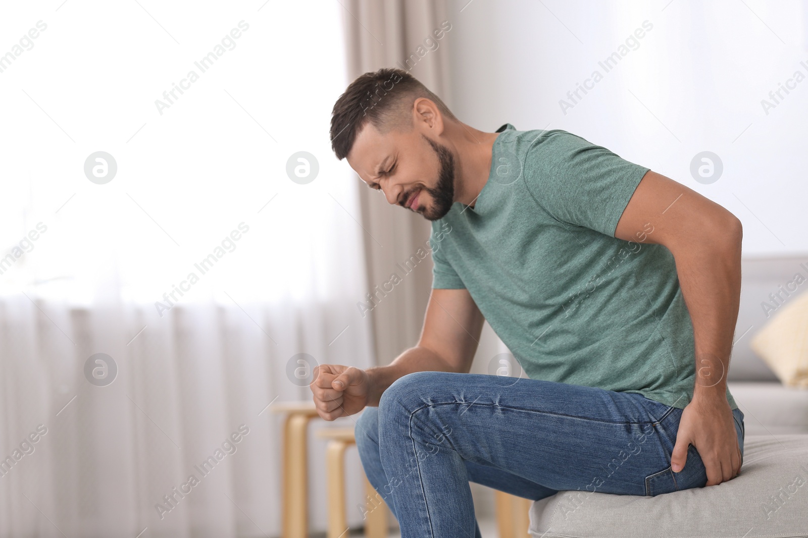 Photo of Man suffering from hemorrhoid in living room