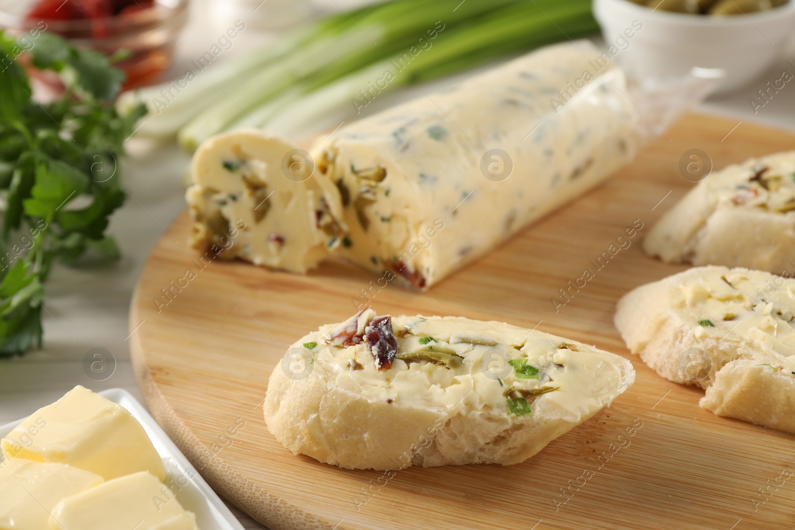 Photo of Tasty butter with olives, green onion, chili pepper and bread on table, closeup