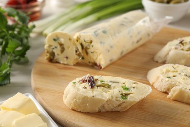 Photo of Tasty butter with olives, green onion, chili pepper and bread on table, closeup