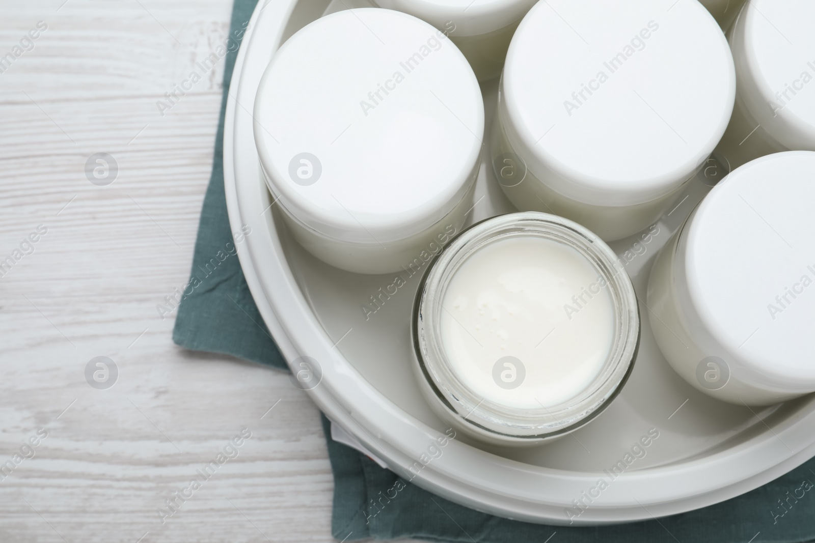 Photo of Modern yogurt maker with full jars on white wooden table, top view