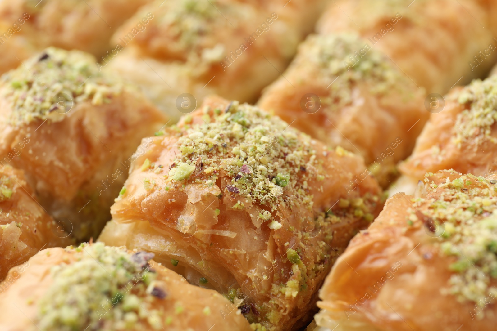 Photo of Delicious fresh baklava with chopped nuts as background, closeup. Eastern sweets