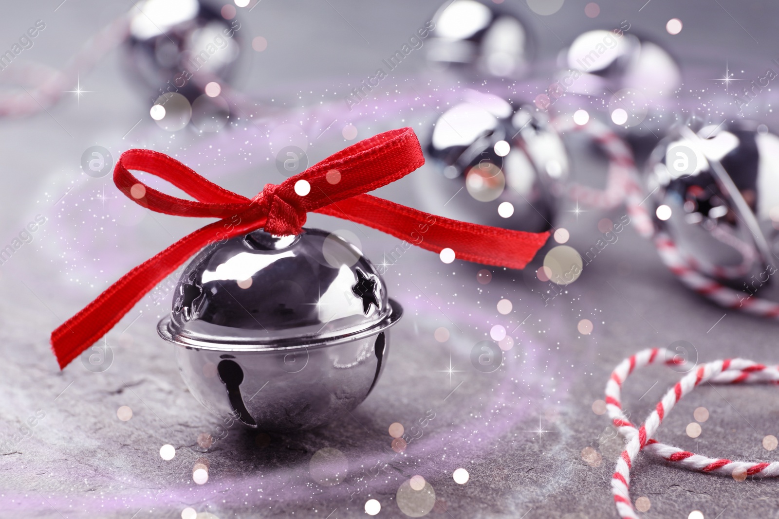 Image of Shiny silver sleigh bell on grey stone table, closeup