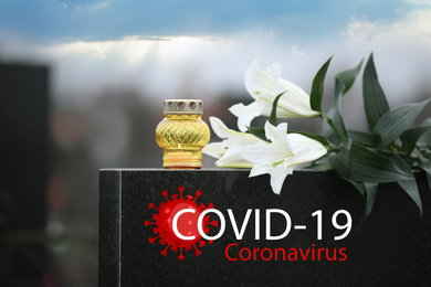 Funeral ceremony devoted to coronavirus victims. White lilies and candle on tombstone outdoors