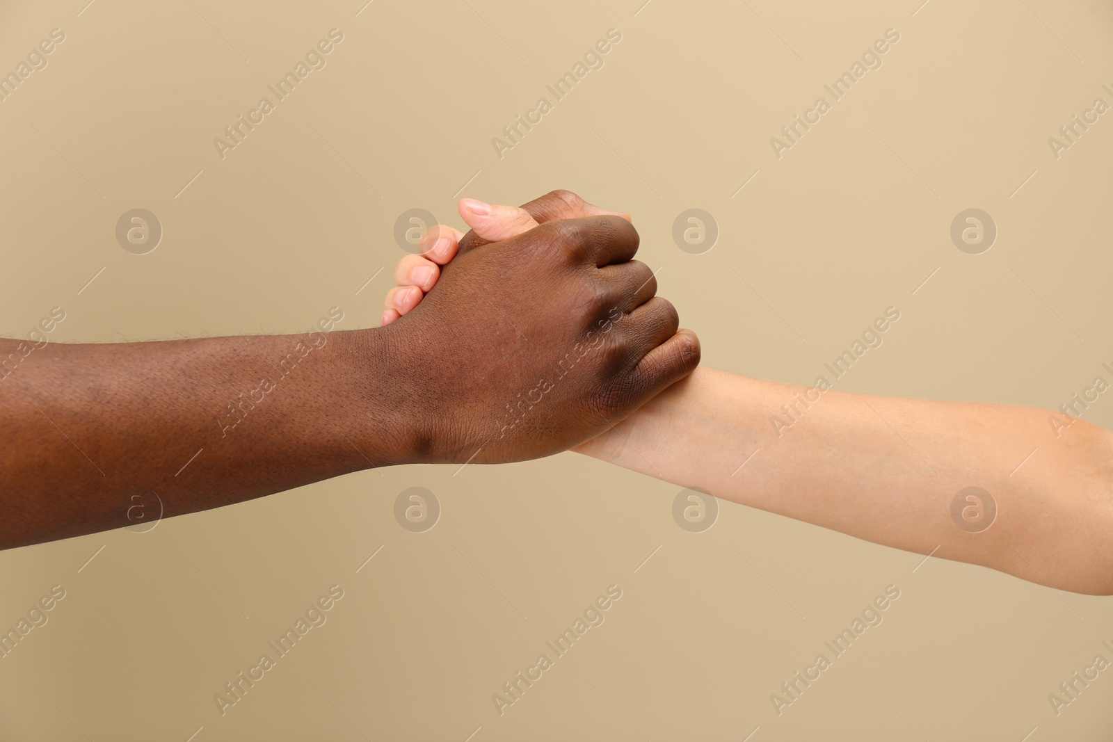 Photo of Woman and African American man clasping hands on beige background, closeup