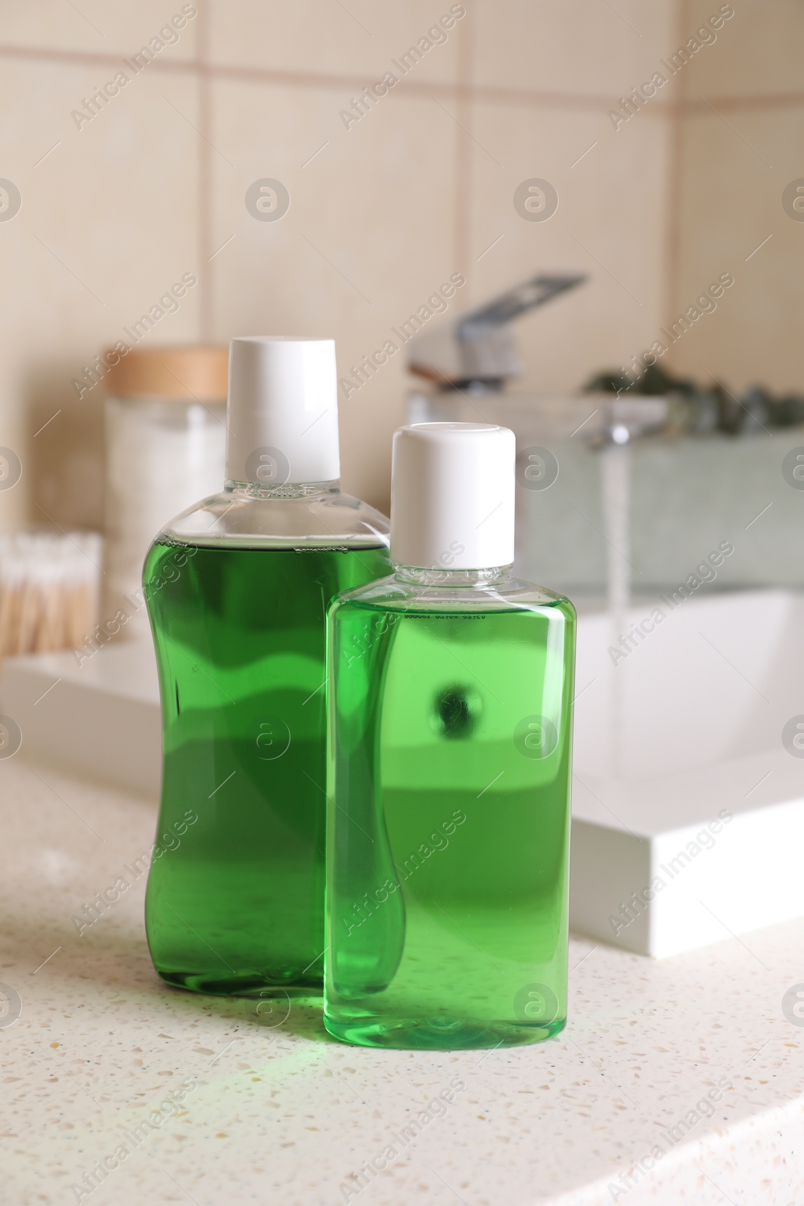 Photo of Fresh mouthwashes in bottles on countertop in bathroom, closeup