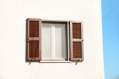 Window with vintage wooden shutters on white wall