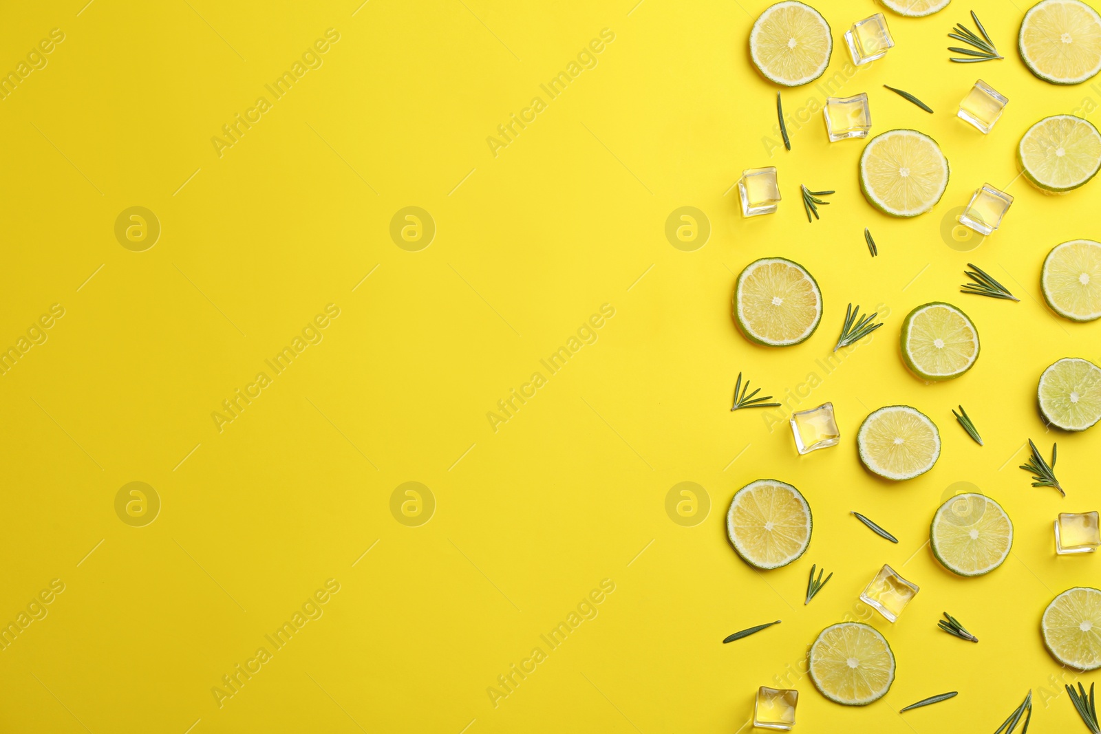 Photo of Lemonade layout with juicy lime slices, rosemary and ice cubes on yellow background, top view. Space for text