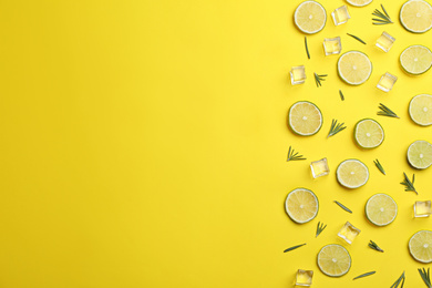 Lemonade layout with juicy lime slices, rosemary and ice cubes on yellow background, top view. Space for text