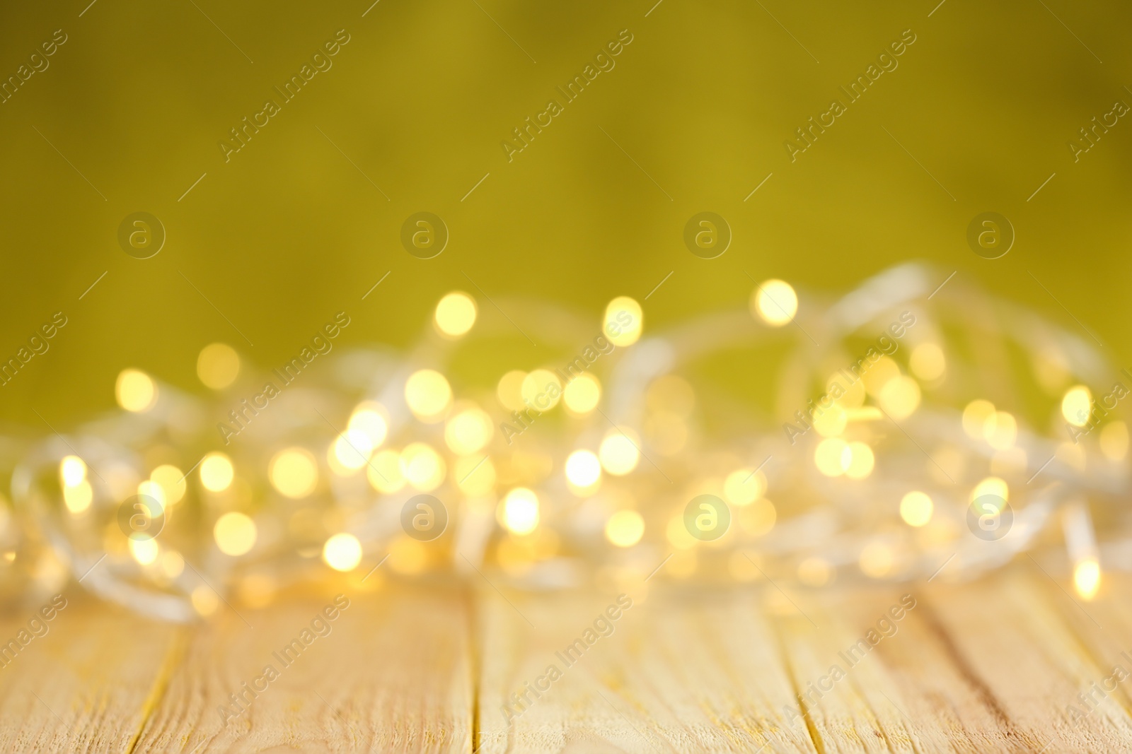 Photo of Yellow Christmas lights on wooden table, blurred view