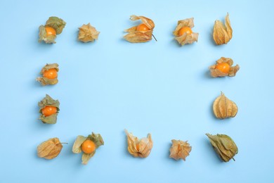 Photo of Ripe physalis fruits with dry husk on light blue background, flat lay. Space for text