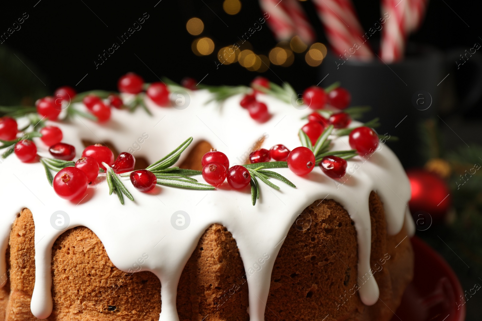 Photo of Traditional Christmas cake decorated with glaze, pomegranate seeds, cranberries and rosemary, closeup