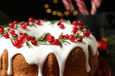 Traditional Christmas cake decorated with glaze, pomegranate seeds, cranberries and rosemary, closeup